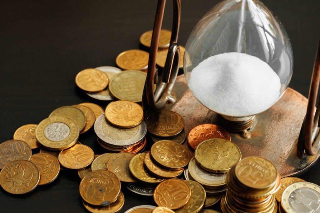 Time is money. Close up of hourglass with money coins